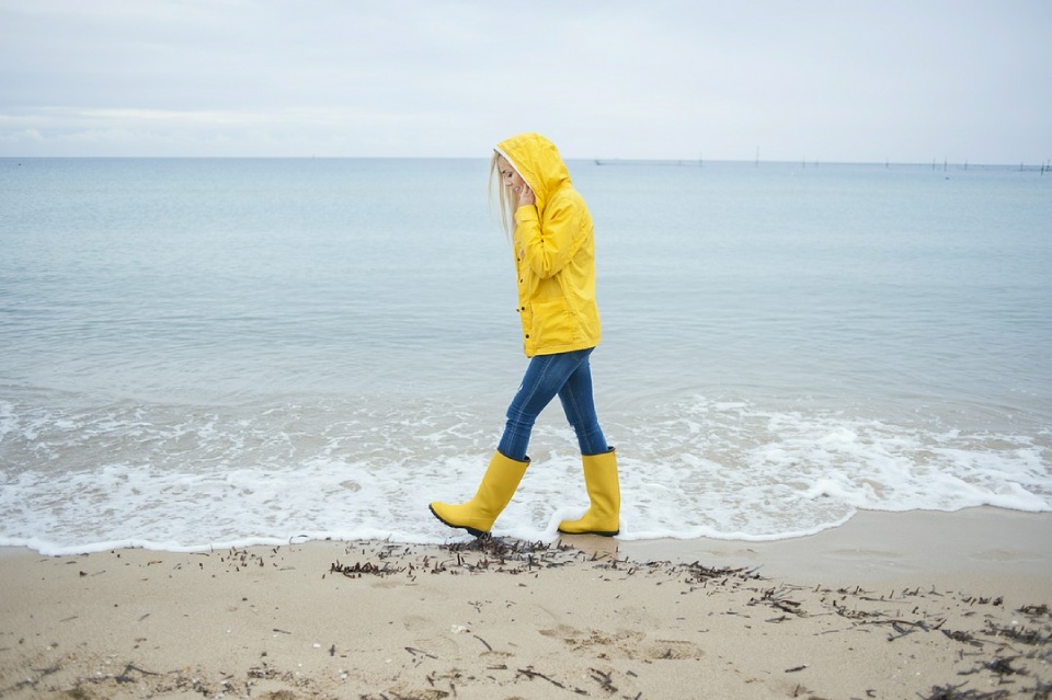 kobieta spacerująca w deszczu na plaży